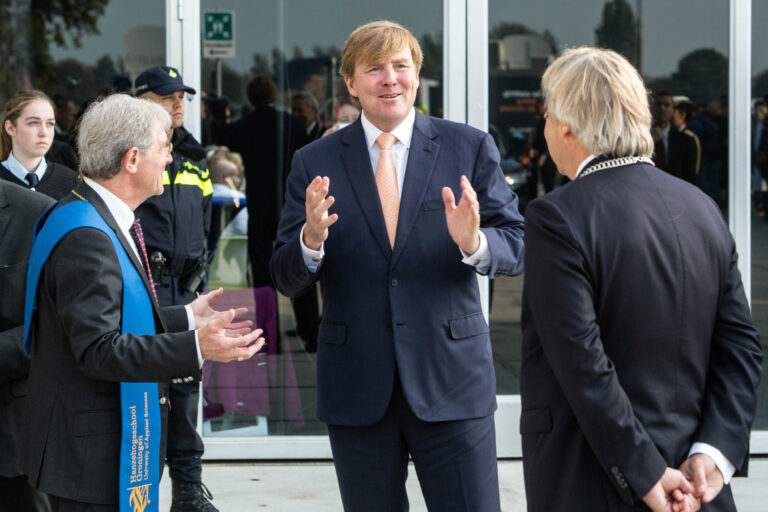 Ik zie een groep mensen die in gesprek zijn met elkaar. Ze zijn formeel gekleed, en er is beveiliging zichtbaar op de achtergrond. De omgeving lijkt bij een modern gebouw te zijn. Helaas kan ik niet zeggen wie de mensen in de foto zijn. Foto door Jan Buwalda uit Groningen.