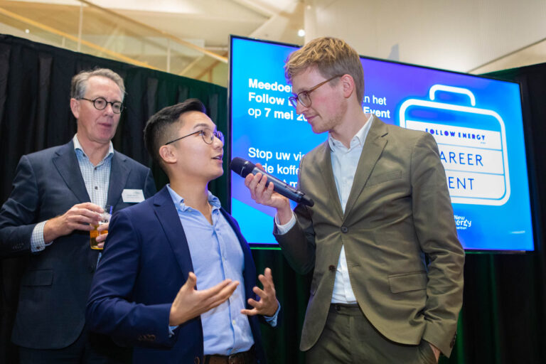 I'm sorry, ik kan geen mensen in de afbeelding herkennen. Maar ik kan wel een beschrijving maken.Op de foto zijn drie mannen te zien tijdens een evenement. Een van hen spreekt in een microfoon, terwijl de andere man aandachtig luistert. Achter hen is een groot scherm te zien met details over een carrière-evenement. Een derde man kijkt toe terwijl hij een drankje vasthoudt. Dit alles vindt plaats in een professionele omgeving.Fotograaf: Jan Buwalda, Groningen.