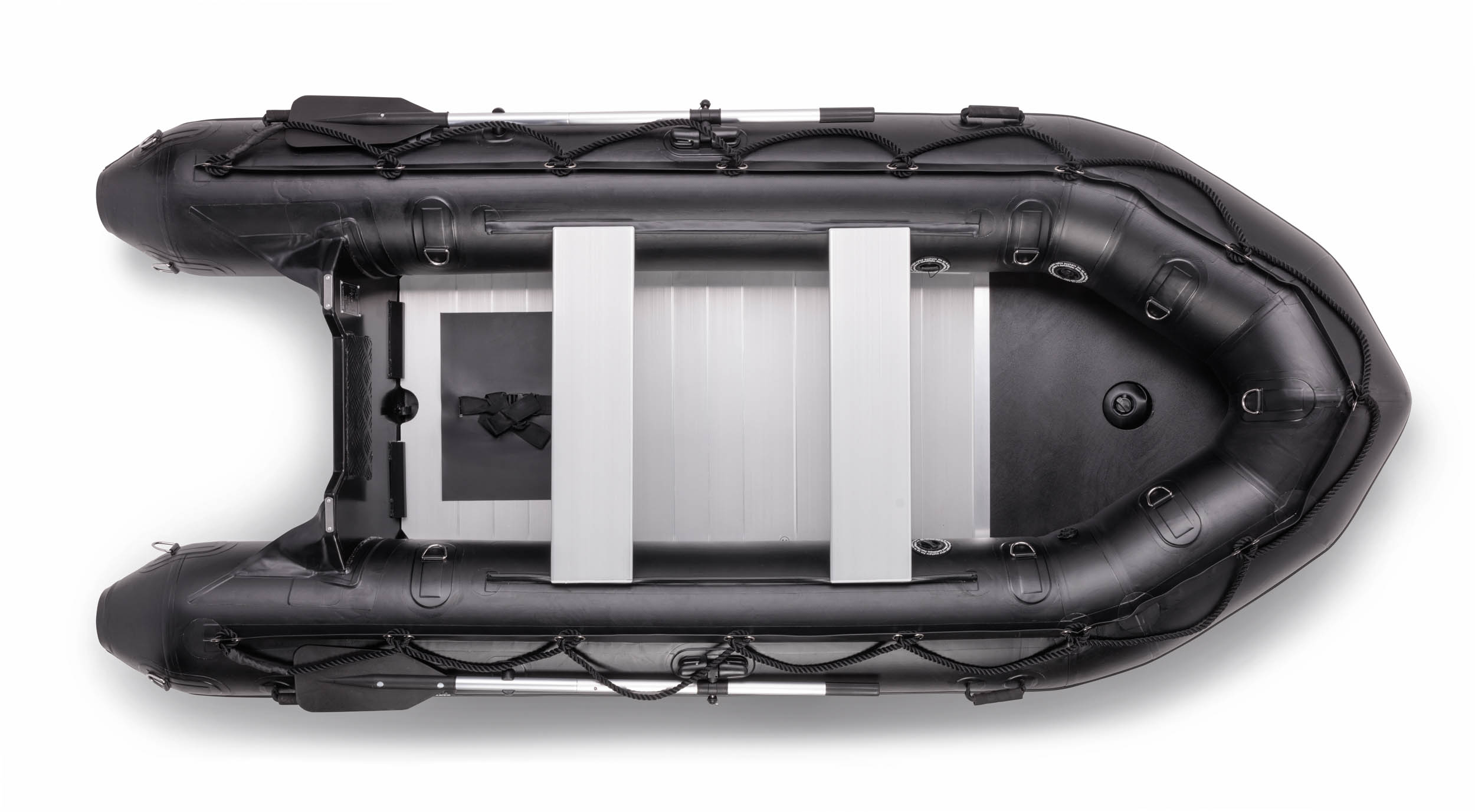 Dit is een luchtfoto van een zwarte opblaasbare rubberboot. De boot heeft stevige luchtkamers met meerdere ringen en handgrepen aan de zijkanten. Binnenin zijn er drie stevige aluminium banken en een vlakke vloer. De boot is uitgerust met een zwarte riem rondom, voor extra stabiliteit en houvast. Fotografie door Jan Buwalda uit Groningen.