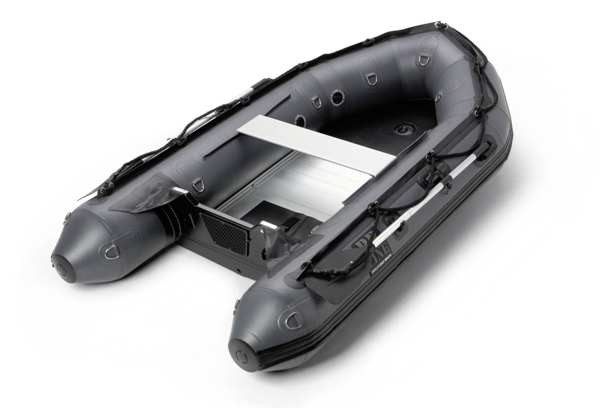 Dit is een afbeelding van een opblaasbare grijze rubberboot, ontworpen voor veelzijdigheid op het water. Het heeft stevige handvatten aan de zijkanten, een aluminium bodem en een bankje in het midden. De boot is omringd door stevige touwen en metalen bevestigingspunten, wat de duurzaamheid benadrukt. De foto is gemaakt door Jan Buwalda in Groningen.