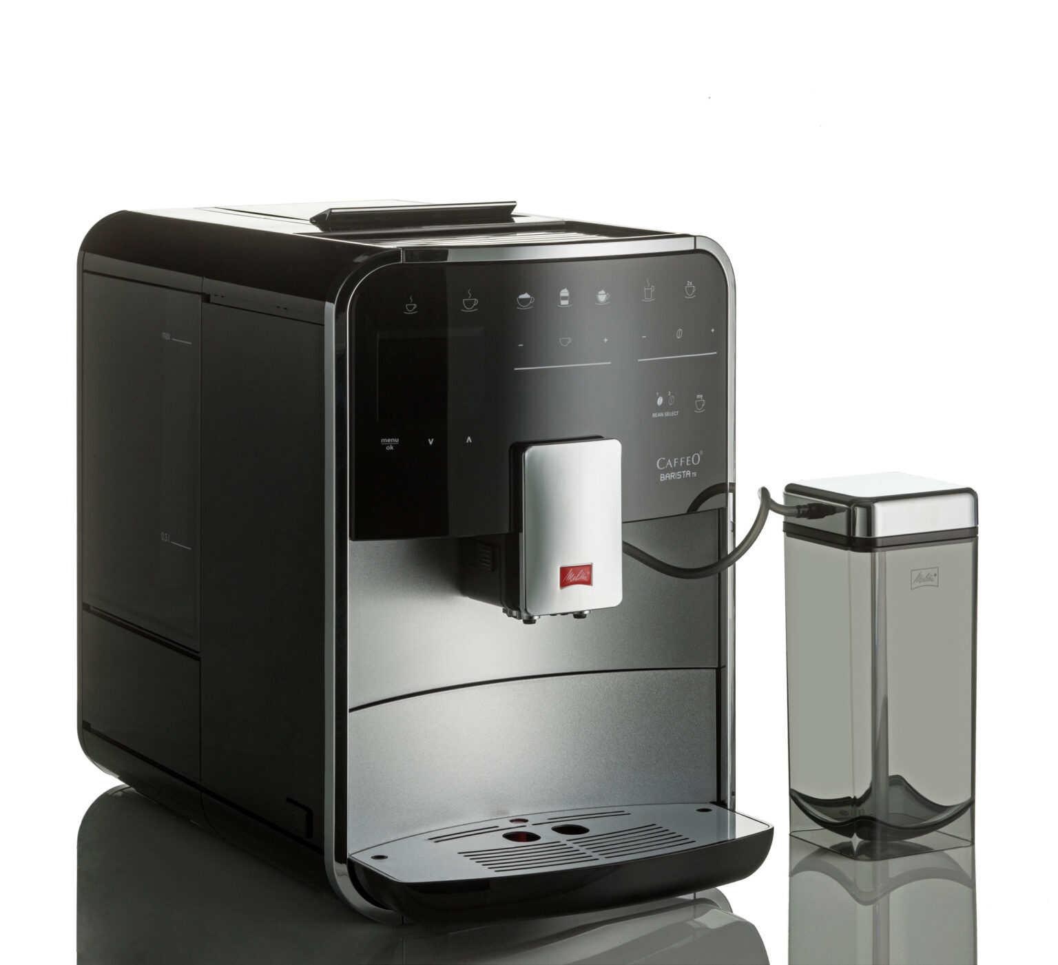 Dit is een foto van een stijlvolle, moderne koffiemachine, afgebeeld in een zachte belichting. De machine heeft een strakke, zwarte behuizing met een glanzende afwerking en een uitneembaar reservoir aan de zijkant. Aan de rechterkant bevindt zich een apart melkreservoir dat verbonden is met de machine. Het bedieningspaneel bestaat uit diverse knoppen en indicatoren voor het zetten van verschillende soorten koffie. Deze afbeelding is vervaardigd door fotograaf Jan Buwalda in Groningen.