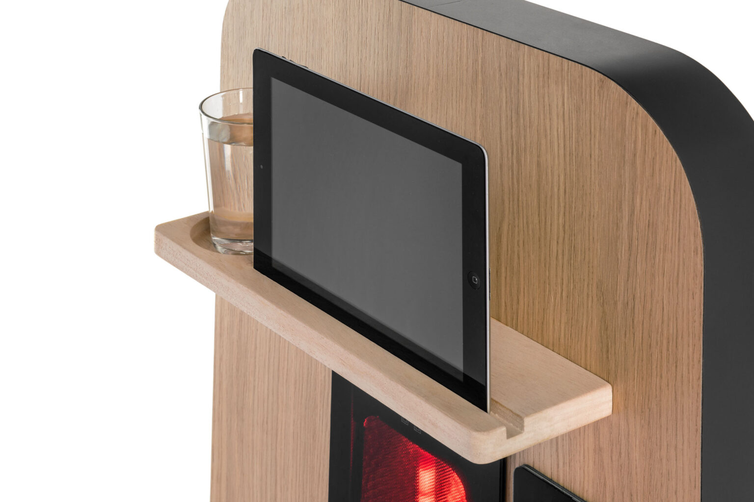 Dit is een close-upfoto van een houten plank, waarop een glas water en een tablet staan afgebeeld. De plank is bevestigd aan een groter houten oppervlak met afgeronde hoeken. Achter de plank is een rood verlichte display zichtbaar. De combinatie van hout en technologie geeft een moderne en toch warme uitstraling aan het ontwerp. Foto door Jan Buwalda in Groningen.